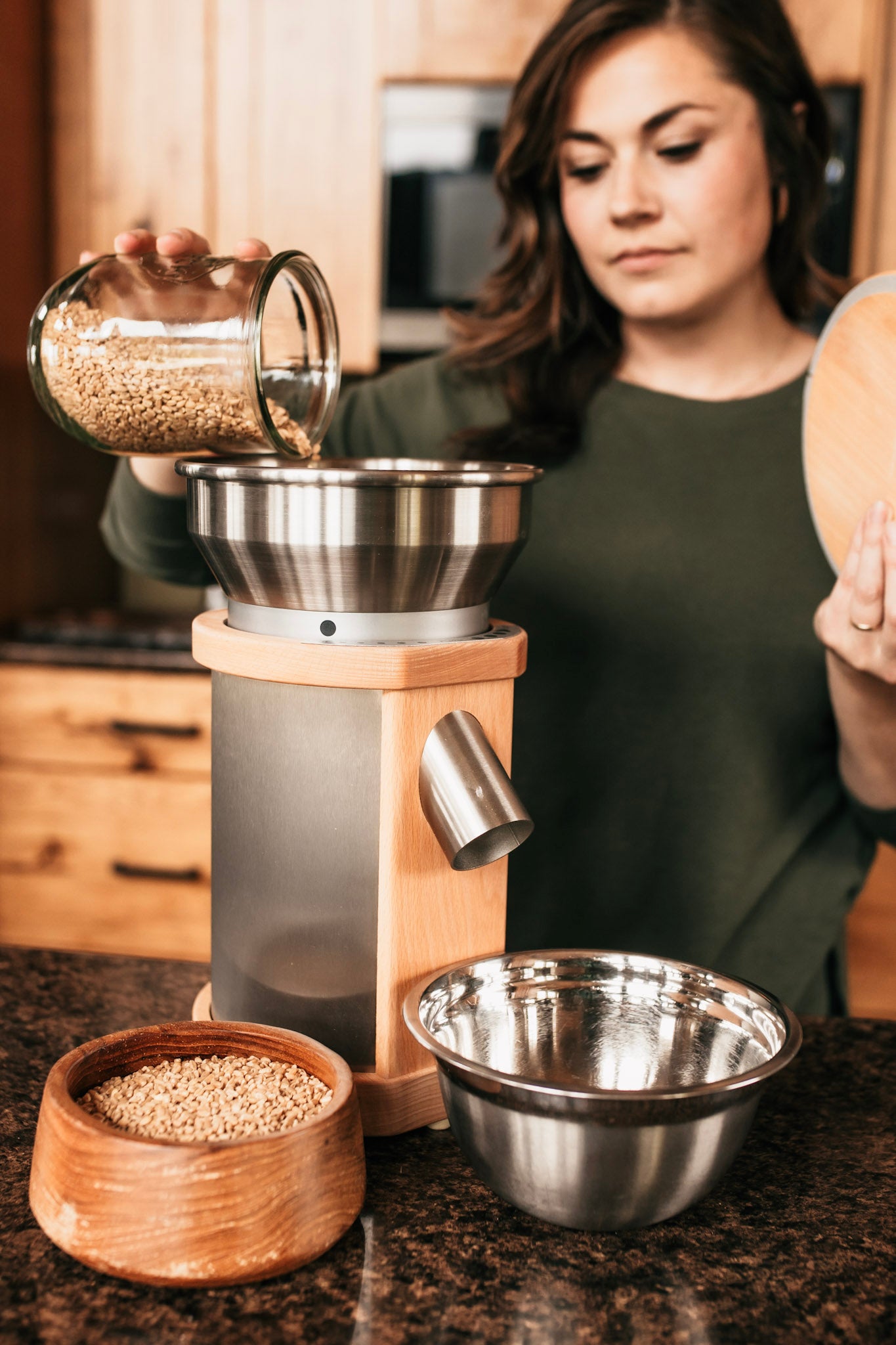 Sarah, the owner of Living Sky Farms pouring whole grains into a Komo Mill