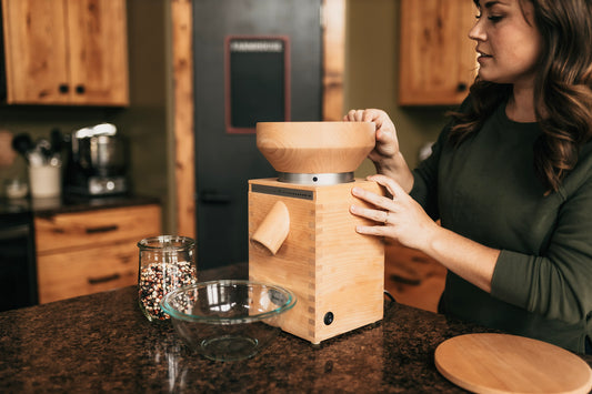 Girl using Komo grain mill with coloured corn