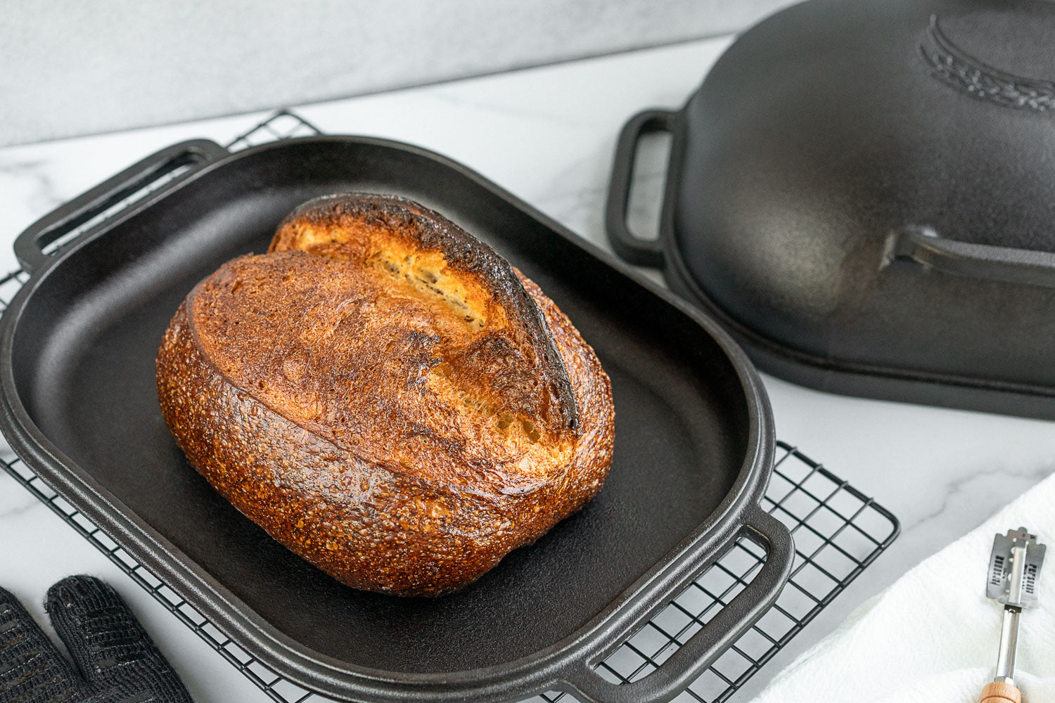 A loaf of bread in a Challenger Breadpan cast iron pan on a cutting board, made with whole grains from Canada.
